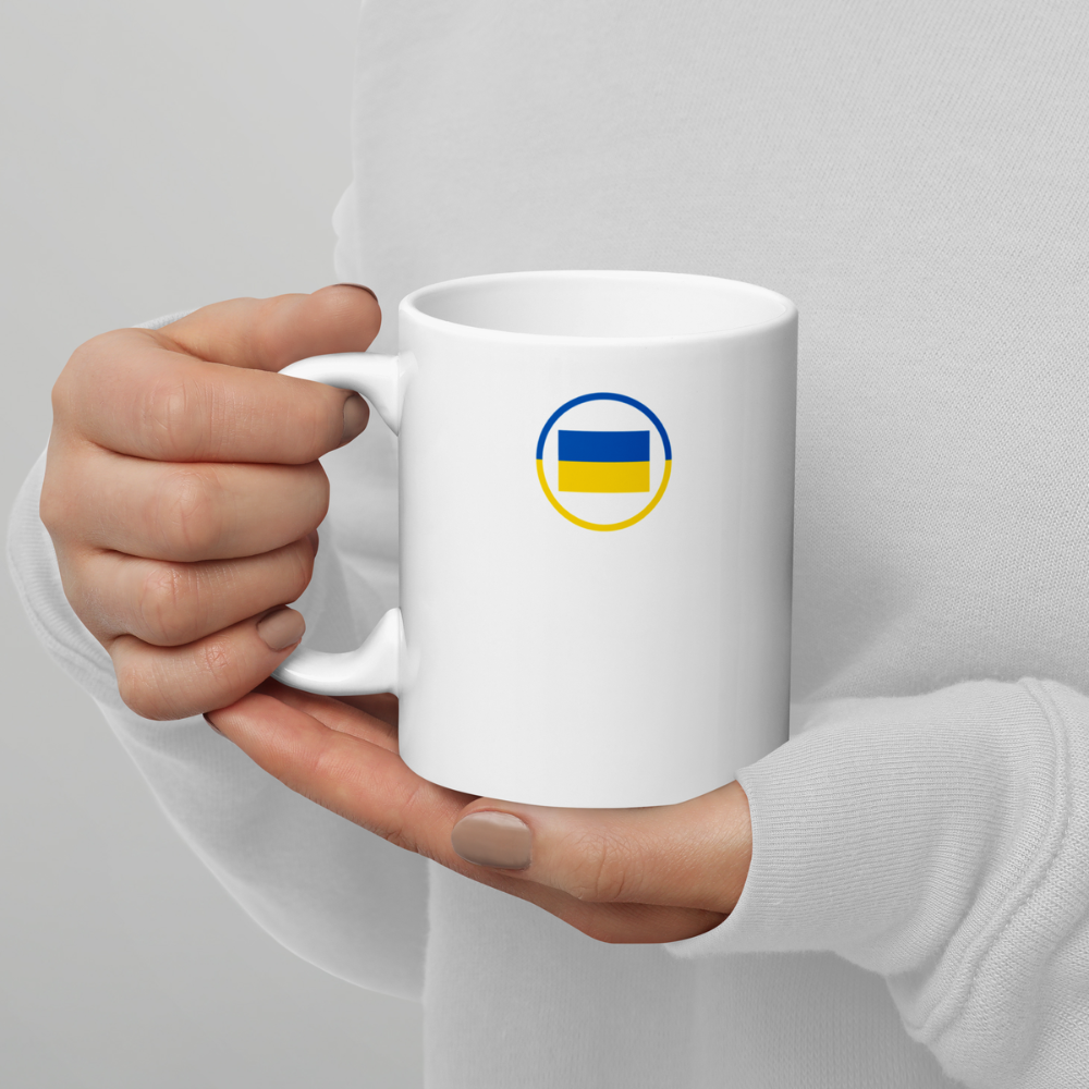 Mug blanc avec drapeau ukrainien tenu en mains Mug en céramique blanc vu de face, tenu à deux mains, avec un motif circulaire bleu et jaune du drapeau ukrainien.