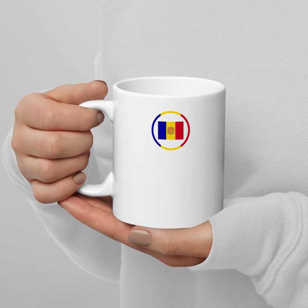Mug blanc tenu en mains avec emblème du drapeau de Andorre sur le côté droit Personne tenant un mug en céramique blanche avec un emblème circulaire du drapeau de Andorre imprimé sur le côté droit.